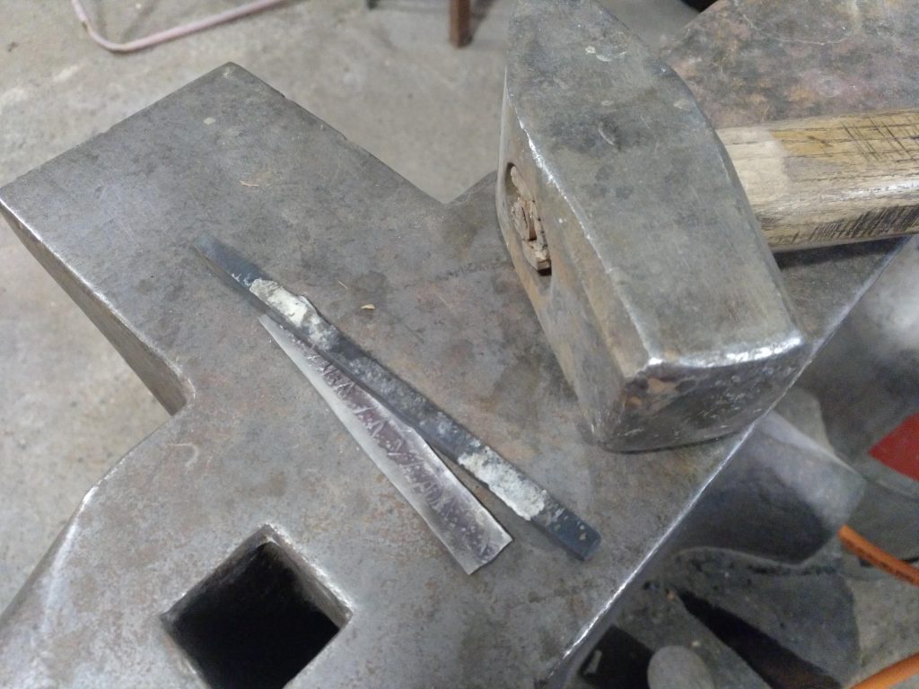 silver with steel die on anvil