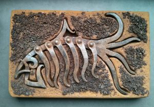 Escultura de pez fósil en hierro y piedra